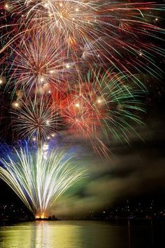 fireworks are lit up in the night sky over water