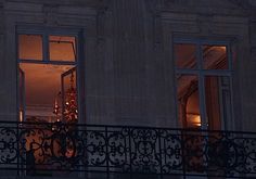 an open window at night with the lights on and balcony railing in front of it