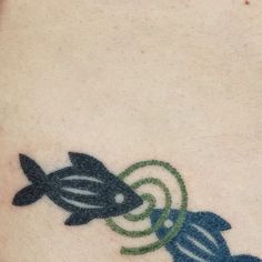 a small tattoo on the side of a person's leg that has two fish in it