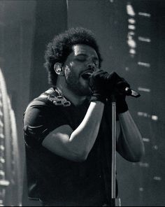 a black and white photo of a man singing into a microphone