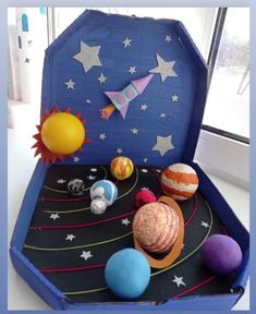 an open suitcase with planets and stars on the inside, in front of a window