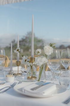 the table is set with white flowers and gold candlesticks for an elegant centerpiece