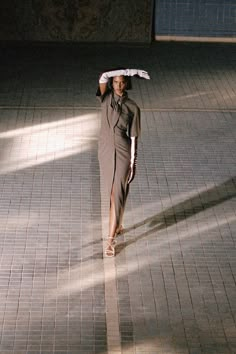 a woman is walking down the street with an umbrella over her head while wearing a dress