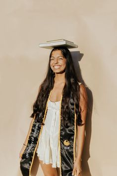 a woman with a hat on her head is standing in front of a beige wall