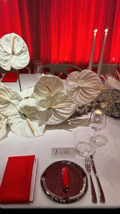 the table is set with red napkins, silverware and white flower centerpieces