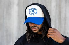 a man with dreadlocks wearing a blue and white hat that says bdb