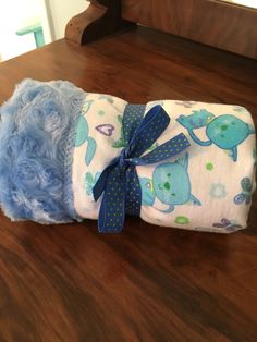 two baby blankets wrapped in blue and white on top of a wooden table next to a stuffed animal