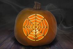 a carved pumpkin with a spider web design on it's front and side, sitting on a wooden surface