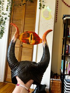 an elephant statue sitting on top of a wooden floor next to a book shelf filled with books