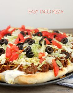 an easy taco pizza with cheese, black olives and lettuce on it