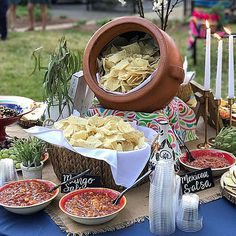 a table topped with bowls and plates filled with food next to candles on top of a blue table cloth