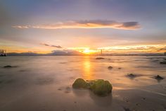 the sun is setting over some rocks in the water