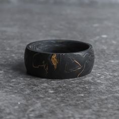 a black and gold ring sitting on top of a cement floor