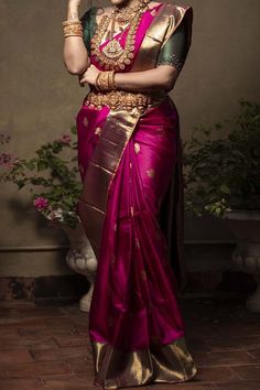 a woman in a red and gold sari with her hands on her chin, posing for