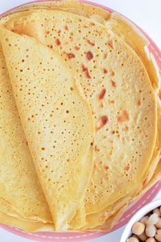 three tortillas on a plate next to some beans and a bowl of peanuts