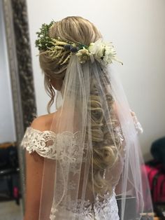 the back of a bride's veil with flowers and foliage on it in front of a mirror