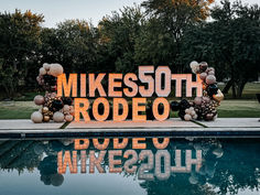 a sign that reads mikesso rodeo next to a pool with balloons and streamers