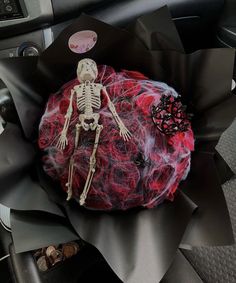 a fake skeleton sitting in the center of a car with red and black decorations on it