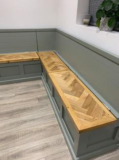 a corner bench in the middle of a room with wood flooring and gray painted walls