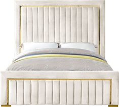 a white bed with gold trimmings and pillows on the headboard, in front of a white background