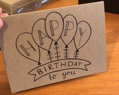 a hand holding up a birthday card with balloons on it and the words, happy birthday to you