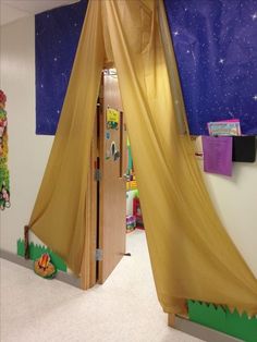 an open door to a playroom with curtains on the ceiling and toys in the background