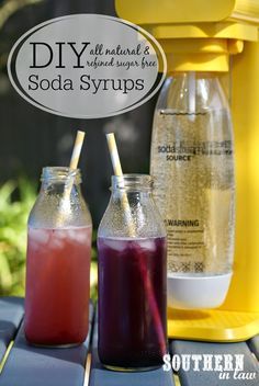 two sodas sitting on top of a table next to a yellow beverage dispenser