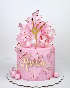 a pink cake decorated with butterflies and a figure