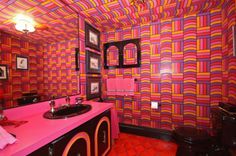 a bathroom with pink and orange walls, red tile flooring and a black sink