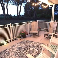 an outdoor patio with chairs and lights on the ceiling, next to a large area rug