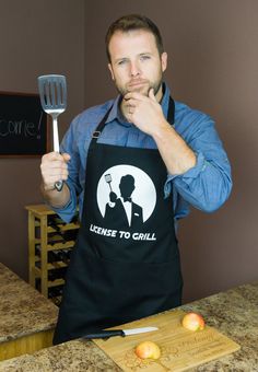 a man holding a spatula in front of his face while standing next to an apple