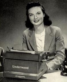 an old photo of a woman sitting at a desk with a typewriter in front of her