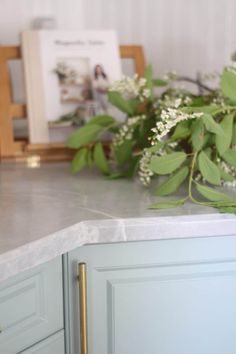 flowers are sitting on the counter top next to a vase with white flowers in it