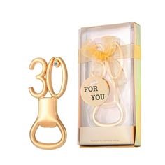 a gold bottle opener with a ribbon on it and a gift box in the background