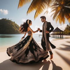 a man and woman dancing on the beach in front of palm trees with water behind them