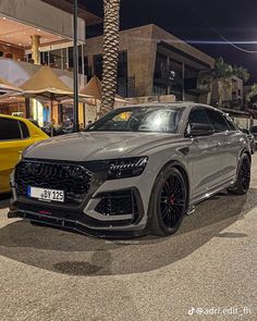 a grey car parked in front of a yellow car on the side of the road