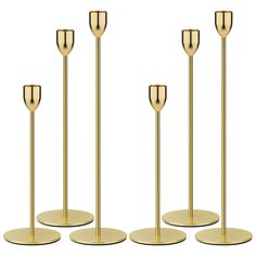 four gold candlesticks on stands with one candle in the middle