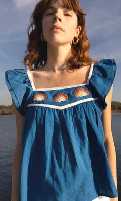 a woman standing in front of the water with her eyes closed