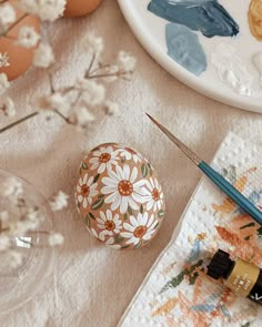 an egg sitting on top of a table next to paintbrushes and other items