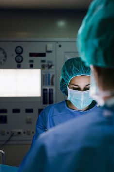 two surgeons in scrubs and surgical masks looking at something on the monitor screen by luma images for stocksy photography