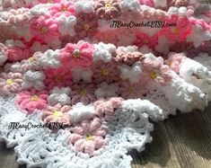 a crocheted blanket with pink and white flowers