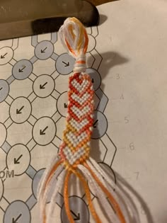 an orange and white beaded object sitting on top of a piece of paper