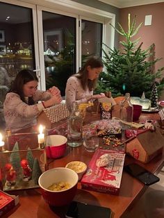 two women sitting at a table with presents and candles