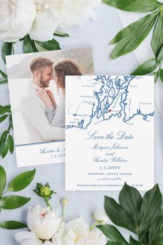 the wedding stationery is laid out on top of flowers and greenery, including white peonies