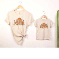 "This Mommy and Me Mama Pumpkin and Mini Pumpkin T-Shirt set is perfect for fall festivities! The t-shirts feature a cute pumpkin design, with \"Mama Pumpkin\" on the adult shirt and \"Mini Pumpkin\" on the child's shirt. Made from comfortable, breathable material, these shirts are great for family outings or cozy nights in. The set is available in various sizes to ensure a perfect fit for both mother and child. Show off your love of autumn with these adorable matching shirts! Key features: - Cute pumpkin design - \"Mama\" on adult shirt - \"Mini\" on child's shirt - Comfortable material - Available in various sizes How to order: 1. Select  Color 2. Select Size/Style 3. Add to Cart 4. If looking to purchase multiple sizes/colors repeat steps 1-3  5. Proceed to Check Out Please take a look Family Letter Print Tops For Fall, Fall Tops With Letter Print, Casual Family T-shirt For Fall, Fall Family Outfits, Sweatshirts Cute, Fall Festivities, Family Outings, Matching Sweatshirts, Mini Pumpkins