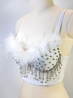 a white dress with feathers and beads on the bust, as well as an attached belt