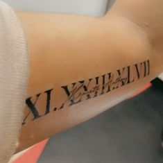 a person with a tattoo on their arm that has roman numerals written on it