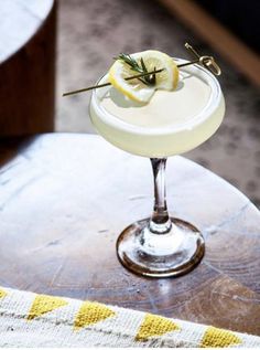 a cocktail with lemon and rosemary garnish on the rim