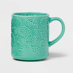 a green coffee mug with sea shells and seashells on the inside, sitting on a white surface