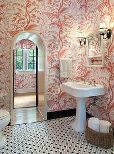 a bathroom with pink and white wallpaper, toilet, sink and mirror in it